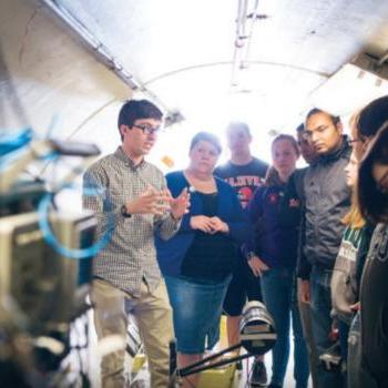 Dr. 扎克·梅塞尔和学生们在爱德华兹加速器实验室的飞行时间隧道里, 位于校园内.